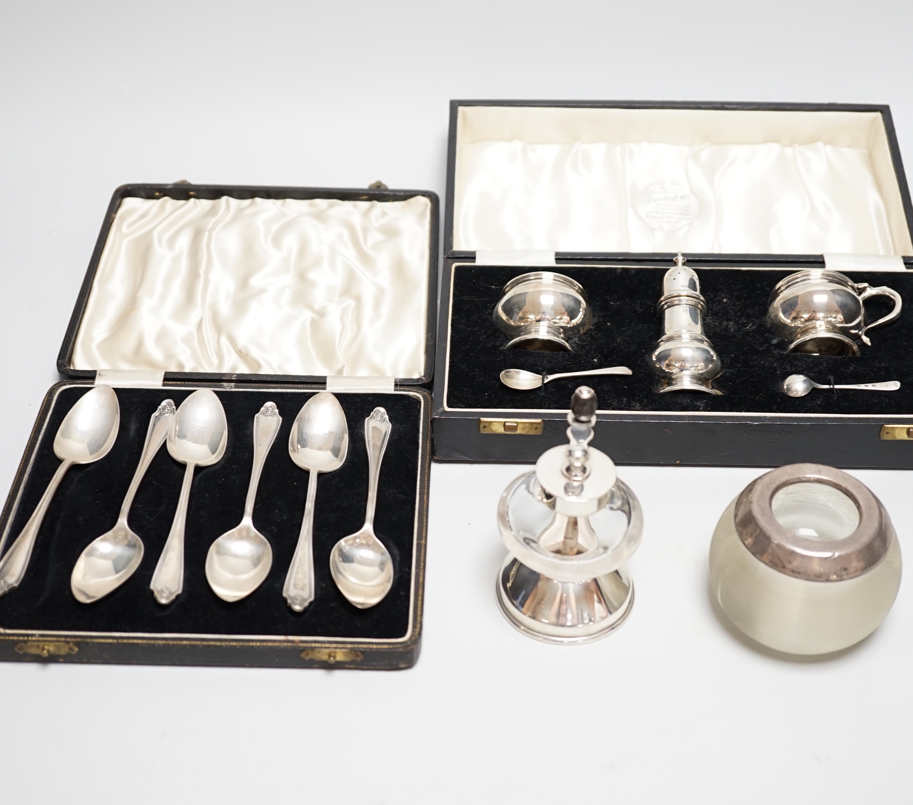 A cased George V silver three piece condiment set with two spoons, London, 1935, a cased set of six silver grapefruit spoons, a silver mounted glass pepper grinder and a white metal mounted glass match strike.